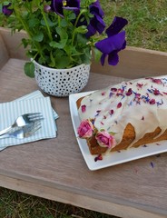 Cake with blossoms and frosting on wood with flower outside