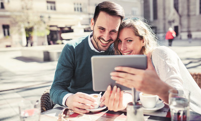 Young couple sitting in the cafe and having fun with tablet. Dating, relationships, love, romance, lifestyle, technology