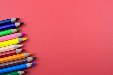 Color Pencils set on red tone color paper. Empty space for text and design. Minimalism concept