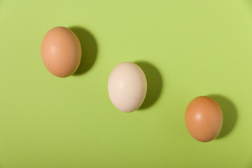 three eggs on green background and with shadows