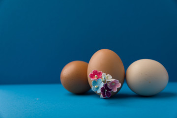 eggs with plush flower corsage on  blue background