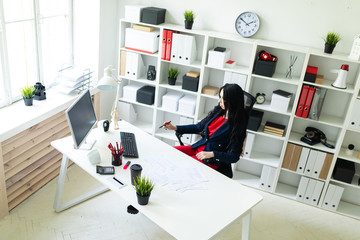 Beautiful young girl fills the documents, sitting in the office at the table.