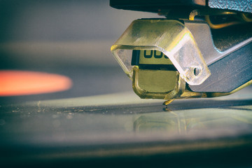 The stylus of the vinyl analog player is in contact with the surface of the rotating LP. Macro....