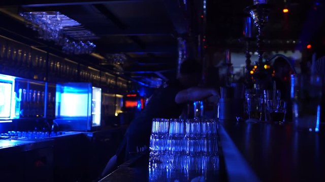 Busy barkeeper working at bar counter in night club, lifestyle, slow-motion