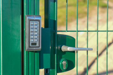 silver intercom on green fence on park entry