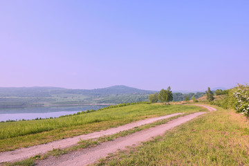 Fototapeta na wymiar Czech landscape with meadow path leading to new lake named Milada and mountains in spring morning