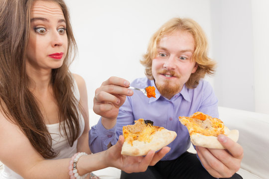 Couple eating pizza, having fun together.