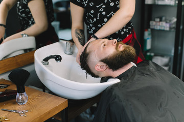 Hairstylist washing client's hair in barber shop.