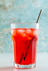red summer tea with berries in a glass with ice and alcohol. summer refreshing drink