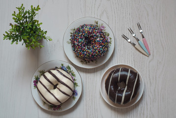 Top view of chocolate donuts served in plates on white wooden table.