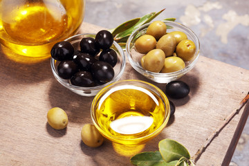 Bottle virgin olive oil and oil in a bowl with some olives