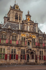 Market Square and Gothic City Hall building facade richly decorated on cloudy day in Delft. Calm and graceful village full of canals and Gothic architecture. Western Netherlands.