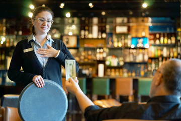 The waitress refuses to receive a tip from the client in the hotel bar. The girl is frustrated....