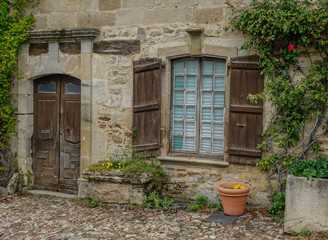 Najac, Midi Pyrenees, France - September 16, 2017: Old stone facade with wooden door and window surrounded by vines
