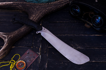 A large knife with a fixed blade. Binoculars and a compass.