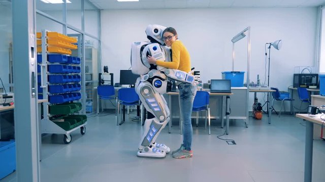 A cyborg and a woman are hugging each other and smiling