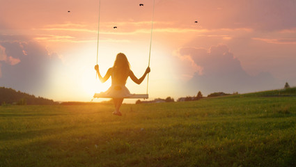 SILHOUETTE: Unrecognizable young woman swaying on swing at golden summer sunrise - obrazy, fototapety, plakaty