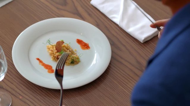 Man food blogger eating bulgur dish with fork and knife in restaurant close up