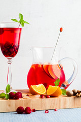 fresh summer red sangria from ripe fruits and berries, as well as wine on the table in glasses and a decanter. spices and mint leaves