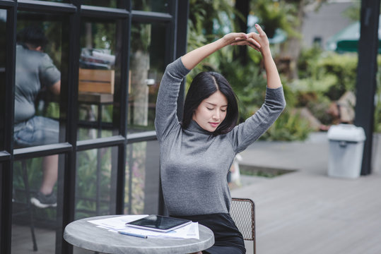 Portrait Of Young Smiling Woman Sitting At Home Office Desk In Front Of Laptop  Stretching With Enjoyment After The Work Is Done  Looking At Screen With Happy Expression