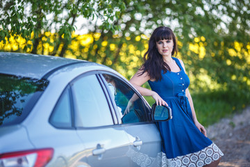 young happy beautiful big size model girl in blue dress near her car
