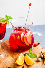 fresh summer red sangria from ripe fruits and berries, as well as wine on the table in glasses and a decanter. spices and mint leaves