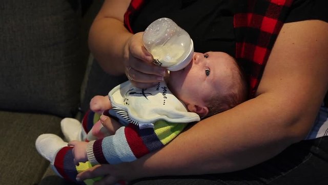 baby drinking milk from bottle wide awake