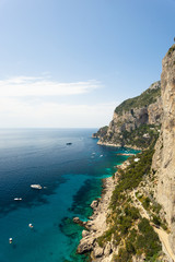 Fototapeta premium Capri Island, Italy - April 29 2018: Boats cruise in the turquoise Water of the beautiful Coastline of Capri