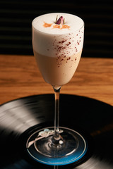 Classical Lucy cocktail on vinyl tray background. Cocktail with Gin, Yogurt, liqueur, Lychee puree, Cardamom syrup, egg white, Lemon juice. Sweet cocktail with spicy taste, close-up