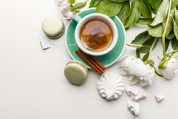 tea with cakes, fruits and flowers on a white table