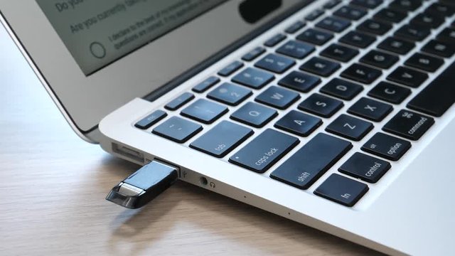 Inserting a USB key in the side port of a laptop computer.