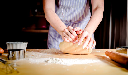 Obraz na płótnie Canvas Female hands making dough on wooden table