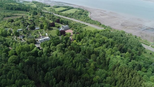 Aerial footage over woodland to a large country house and gardens near the village of Langbank on the south shore of the Firth of Clyde.