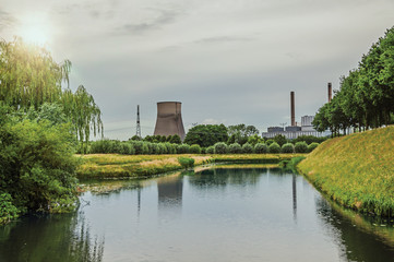 View of canal and gardens with nuclear power plant in background on cloudy day, near the village of Geertruidenberg. A small, friendly place near Aakvlaai Park and Breda. Southern Netherlands.