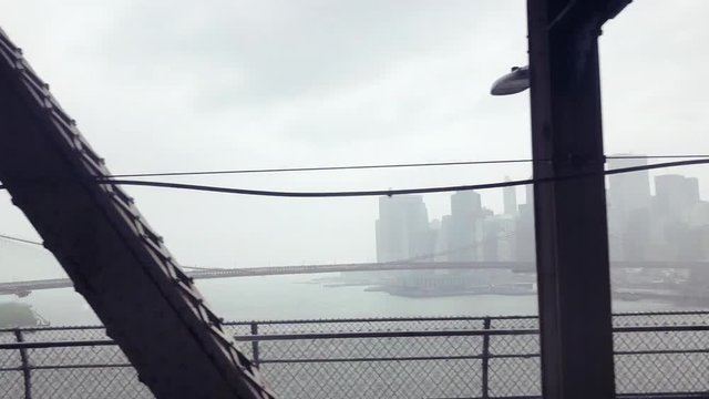Time-lapse view of a subway train ride across the Manhattan Bridge with a view of the NYC skyline on a misty morning