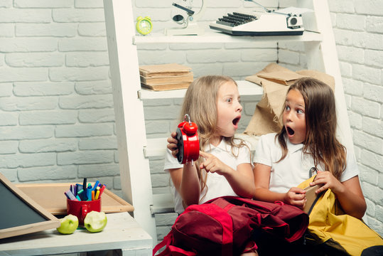 alarm clock in hands of schoolgirls. alarm clock show late time.