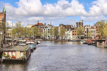Tourist boat in an Amsterdam canal surrounded with typical Dutch old houses.