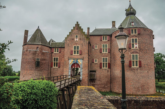 Medieval Ammersoyen Castle with its brick towers, wooden bridge and green garden on cloudy day. Near to the historic and vibrant city of s-Hertogenbosch. Southern Netherlands
