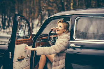 fashion and retro style, fashion model in winter fur coat drives retro car.