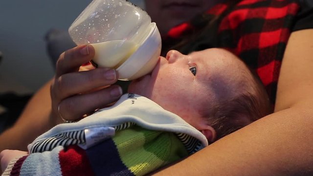newborn baby drinking milk from bottle close up