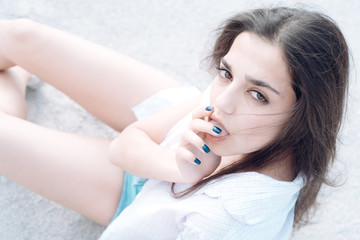 Woman on calm face with make up, floor on background, defocused. Girl with long hair looking at camera while licking her fingers. Lady looks sensual and tender, close up. Sensuality concept.