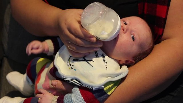 newborn baby bottle fed by mother in warm light