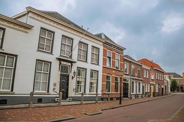 Street with brick houses on cloudy day in the village of Geertruidenberg. A small, friendly place near the Aakvlaai Park and Breda. Southern Netherlands.