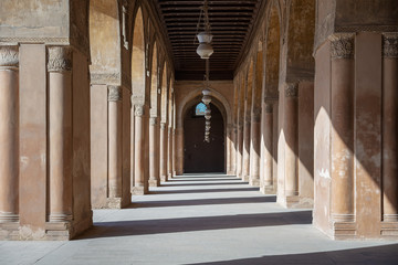 Obraz premium One of the passages surrounding the courtyard of the Mosque of Ahmad Ibn Tulun framed by huge decorated arches, old Cairo, Egypt
