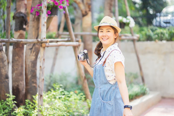 Outdoor summer lifestyle portrait of pretty young Asian woman having fun,she look at camera screen, Young Photographer making pictures in hipster style