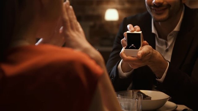 Man giving an engagement ring to his girlfriend at the restaurant