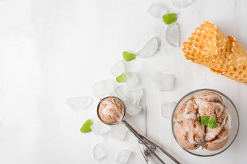 Chocolate ice cream with mint and waffle cone, and a spoon for ice cream. A top view, and with an empty space for an inscription