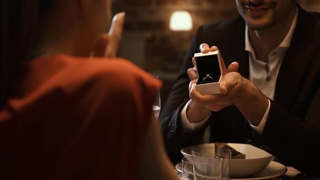 Man giving an engagement ring to his girlfriend at the restaurant