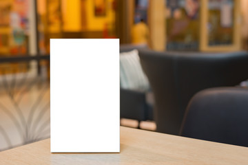 Mock up Label the blank menu frame in Bar restaurant ,Stand for booklets with white sheets paper acrylic tent card on wooden table cafeteria blurred background can inserting the text of the customer.