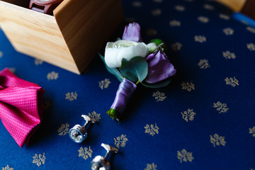 Flower boutonniere. A men's set of accessories on an old wooden chair with a soft blue seat. Set of accessories for a business meeting.
